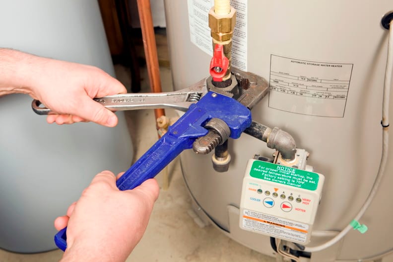 Plumber repairing water heater pipe connection in Wildwood, Georgia home